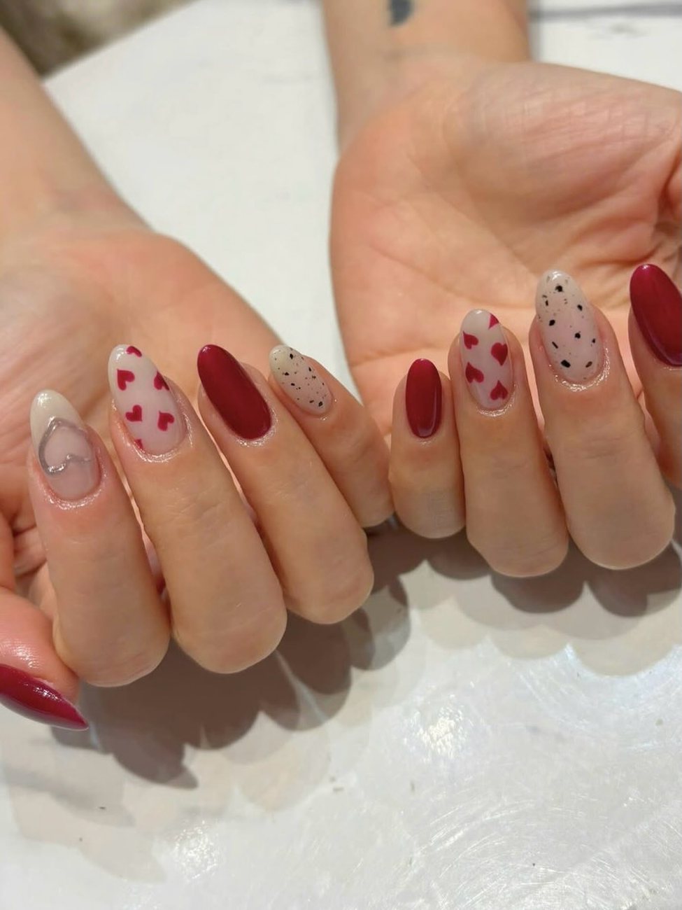 Twee handen met rode nagels, hartjes en stipjes